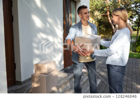 Two young people looking involved while packing for the moving to a new location Two young people looking involved while packing for the moving to a new location 128246846