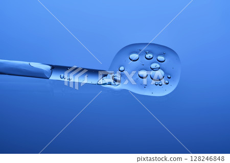 The beautiful texture of the hyaluronic serum with a pipette on a blue background. The beautiful texture of the hyaluronic serum with a pipette on a blue background. 128246848