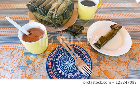 Glutinous rice cakes wrapped in banana leaves called suman or budbud paired with coffee, traditional and authentic local Filipino snack from the Philippines 128247082