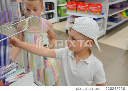 Brother and sister choose school accessories for school at the market 128247238