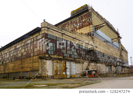 Abandoned factory with rusty metal panels and weathered concrete exterior Abandoned factory with rusty metal panels and weathered concrete exterior 128247274