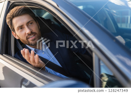 Excited businessman sitting in the car and looking emotional 128247349