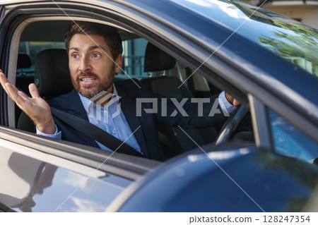 Excited businessman sitting in the car and looking emotional Excited businessman sitting in the car and looking emotional 128247354