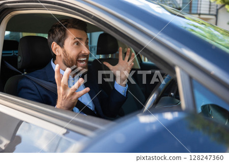 Excited businessman sitting in the car and looking emotional Excited businessman sitting in the car and looking emotional 128247360