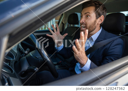 Excited businessman sitting in the car and looking emotional 128247362