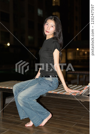 Portrait of beautiful Asian woman at night at pool during holiday Portrait of beautiful Asian woman at night at pool during holiday 128247597