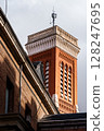 Architectural details of a brick building's tower rise into the sky in Madrid, Spain. 128247695
