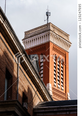 Architectural details of a brick building's tower rise into the sky in Madrid, Spain. 128247695