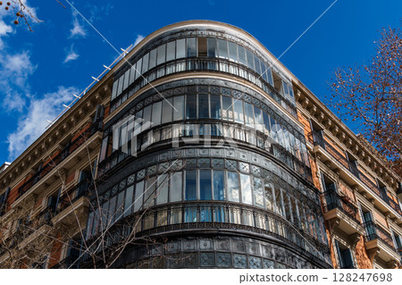 Majestic architecture featuring intricate ironwork and glass in Madrid against a brilliant blue sky. 128247698