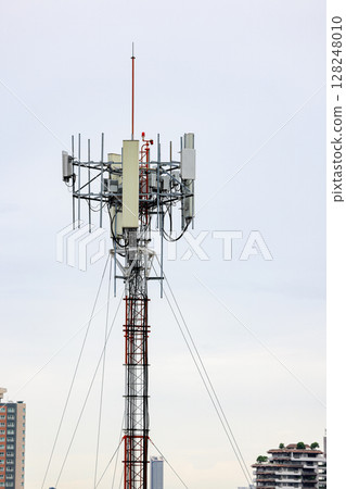 Wireless Communication Antenna pole, Mobile phone mast antenna pole on top of dilapidated building 128248010