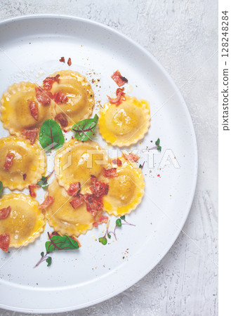fresh ravioli, with butter, spices and herbs, fried bacon, on the table, top view, light background, no people, 128248284