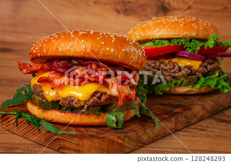 two burgers with beef patty, fried bacon, cheddar cheese, tomatoes, homemade, no people, 128248293