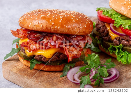 two burgers with beef patty, fried bacon, cheddar cheese, tomatoes, homemade, no people, 128248302