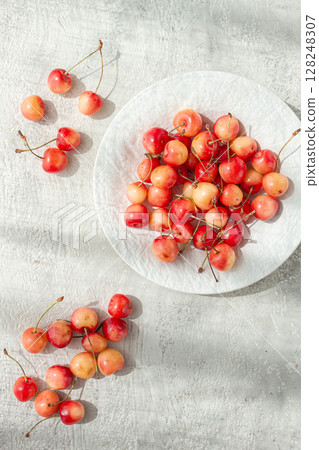 yellow cherries on a white platter, scattered on the table, natural light, top view, 128248307