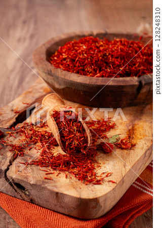 Spice saffron threads, in a wooden bowl, on a wooden table, top view, close-up, 128248310