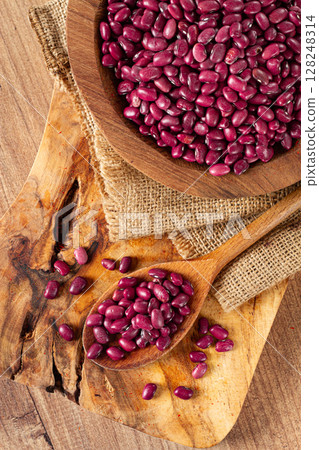 Red beans, laid out in a wooden bowl, on a chopping board, rustic style, covered with burlap, top view, close-up, 128248314