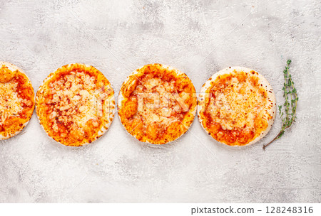 Four pizzetta Margaritas, on a light grey surface, top view, Four pizzetta Margaritas, on a light grey surface, top view, 128248316