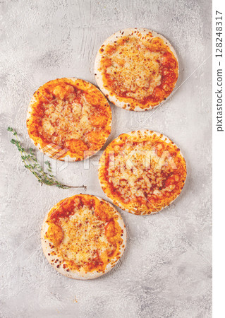 Four pizzetta Margaritas, on a light grey surface, top view, 128248317