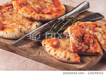 Four pizzetta Margaritas, on a cutting board, on a light gray surface, top view, 128248322