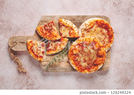 Four pizzetta Margaritas, on a cutting board, on a light gray surface, top view, Four pizzetta Margaritas, on a cutting board, on a light gray surface, top view, 128248324