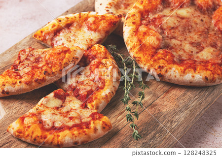Four pizzetta Margaritas, on a cutting board, on a light gray surface, top view, Four pizzetta Margaritas, on a cutting board, on a light gray surface, top view, 128248325