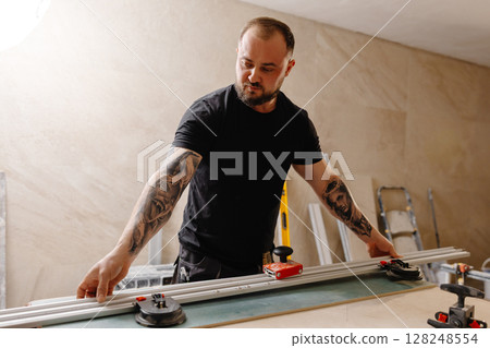 Craftsman working on ceramic tile using tile cutter in workshop Craftsman working on ceramic tile using tile cutter in workshop 128248554