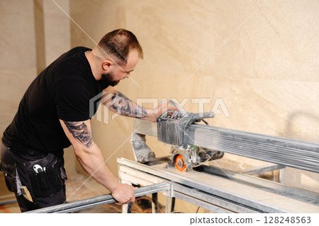 Construction worker cutting ceramic tiles using professional machine Construction worker cutting ceramic tiles using professional machine 128248563