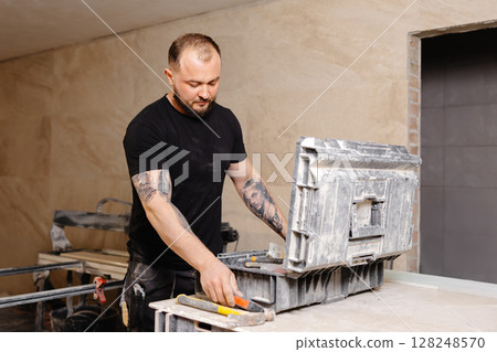 Construction worker taking hammer from toolbox during renovation works Construction worker taking hammer from toolbox during renovation works 128248570