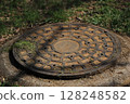 A manhole covered with dirt and grass 128248582