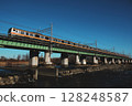 A Chuo Line Rapid Train (E233 Series) crossing a railway bridge in the morning sun 128248587