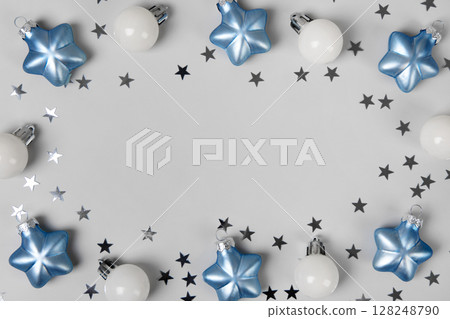 Blue and white Christmas tree balls with silver glitter stars on a gray background with space for text in the center. Christmas and New Year postcard. Flat lay, copy space Blue and white Christmas tree balls with silver glitter stars on a gray background with space for text in the center. Christmas and New Year postcard. Flat lay, copy space 128248790