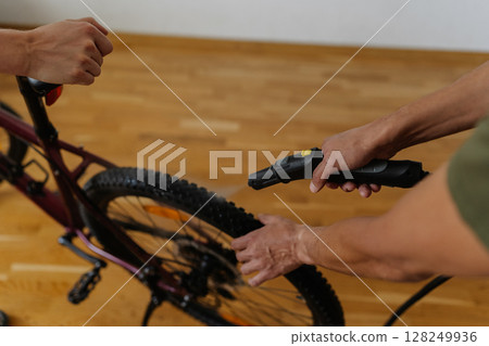 Two professional mechanics steam cleaning mountain bike wheel, maintaining precision and cleanliness in bicycle repair workspace, close-up. Concept of professional bicycle maintenance and service. 128249936