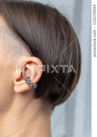 Close-up of girl's earring in her ear. Beautiful jewelry women's decoration. Studio photography. Vertical photo. High quality photo 128250084