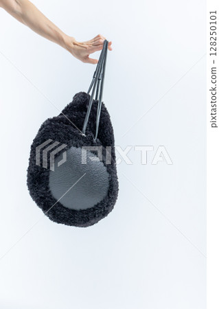 Female hand holding black fashionable bag on light background. Vertical photo. High quality photo 128250101