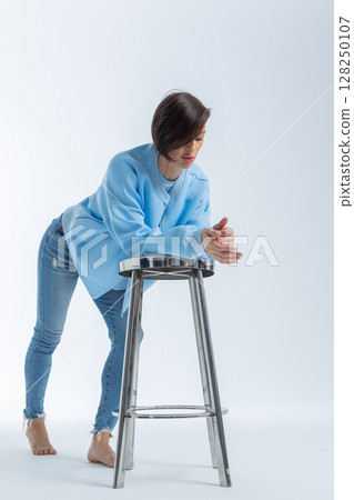 Beautiful woman of model appearance. Girl in blue clothes on grey background. Pretty female with trendy makeup posing in studio. Vertical photo. High quality photo Beautiful woman of model appearance. Girl in blue clothes on grey background. Pretty female with trendy makeup posing in studio. Vertical photo. High quality photo 128250107
