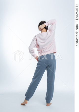 Beautiful woman of model appearance. Girl in light pink jumper and gray trousers on light background. Pretty female with trendy makeup posing in studio. Vertical photo. High quality photo Beautiful woman of model appearance. Girl in light pink jumper and gray trousers on light background. Pretty female with trendy makeup posing in studio. Vertical photo. High quality photo 128250112