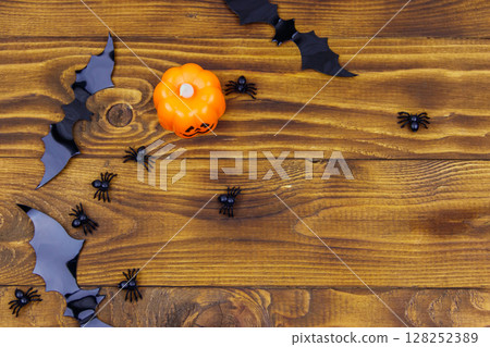 Halloween composition with jack-o-lantern, spiders and bats on wooden background. Top view, copy space Halloween composition with jack-o-lantern, spiders and bats on wooden background. Top view, copy space 128252389