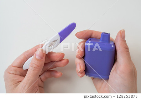 Woman holding pregnancy test and e-cigarette.  128253873