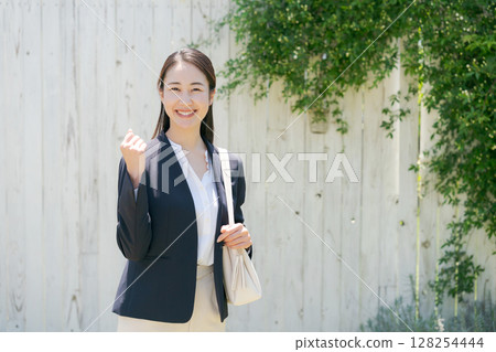 一位身穿西裝的女士站在白牆前 一位身穿西裝的女士站在白牆前 128254444