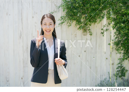 一位身穿西裝的女士站在白牆前 128254447