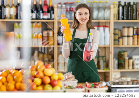 Young woman seller offering soda in grocery store Young woman seller offering soda in grocery store 128254582