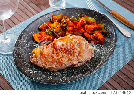 Piece of fried veal with stewed vegetables in restaurant 128254640
