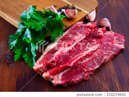 Raw sliced marbled beef meat with parsley and condiments Raw sliced marbled beef meat with parsley and condiments 128254692