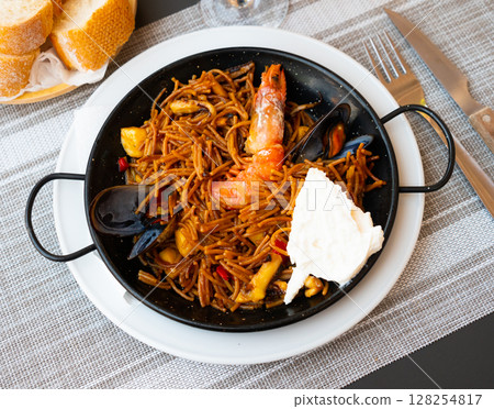 Spanish seafood fideua, noodle paella with aioli Spanish seafood fideua, noodle paella with aioli 128254817