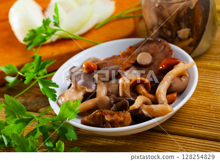 Various pickled mushrooms in plate with onions and parsley closeup Various pickled mushrooms in plate with onions and parsley closeup 128254829