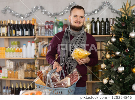Middle-aged guy choosing chips in a Christmas-decorated store 128254846