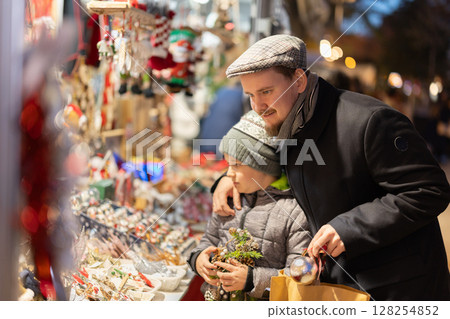 Man with son in outdoor souvenir shop examines Christmas toys 128254852