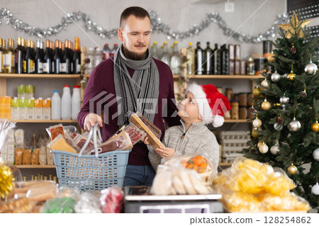 Dad and son are choosing sweets for New Year celebration in supermarket Dad and son are choosing sweets for New Year celebration in supermarket 128254862