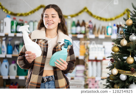 Young woman choosing cleaning spray in store during Christmas Young woman choosing cleaning spray in store during Christmas 128254925
