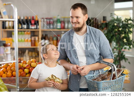 Visiting store, father and son is looking at something on shelf of showcase. 128255104